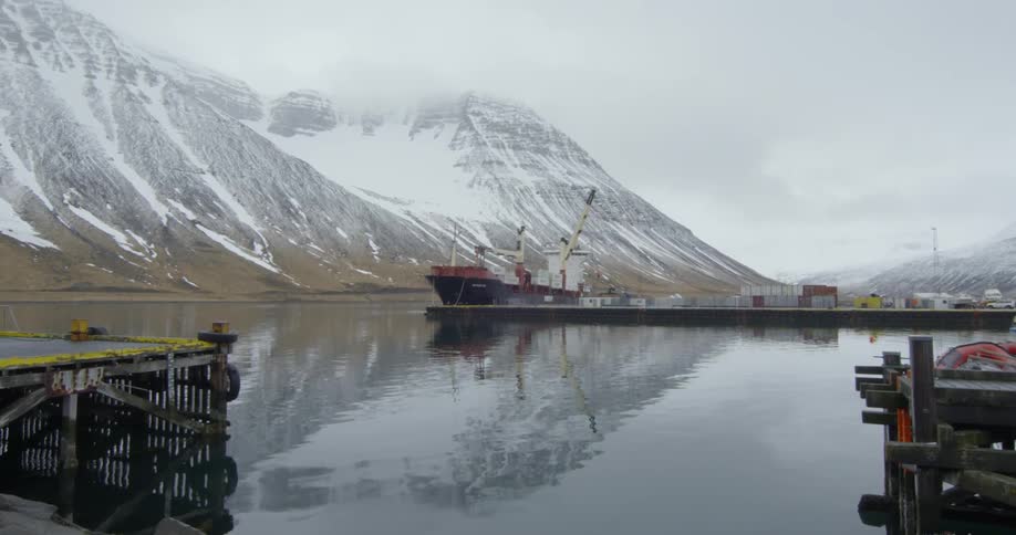 A ship is docked and a large mountain is in the distance