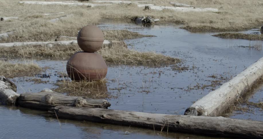 Two rusted metal balls sit stacked in the water