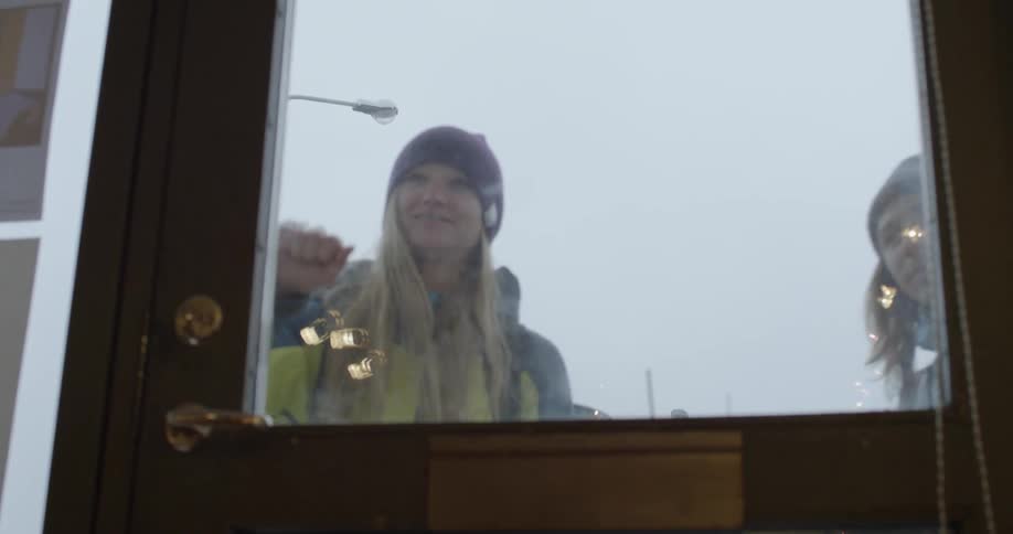 A woman and man approach a door and knock