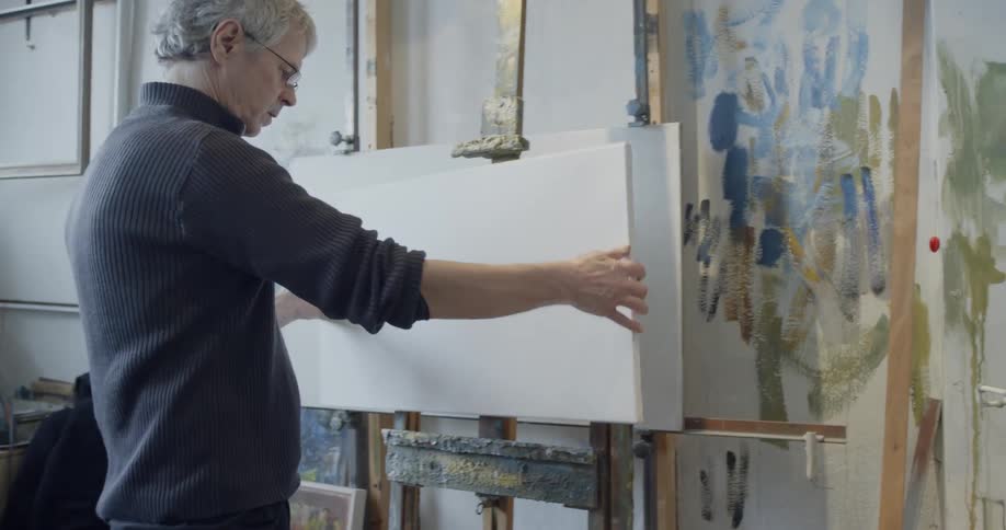 An painter places a canvas on an easel