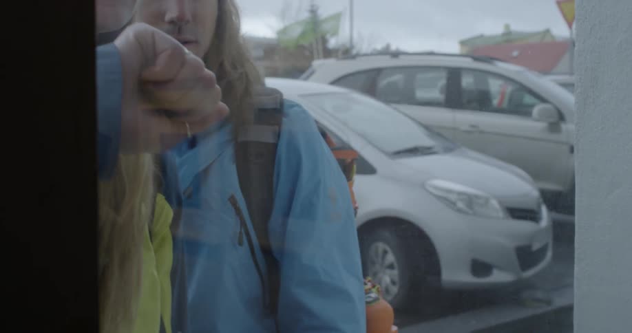 Two people walk up to a glass door and knock on it