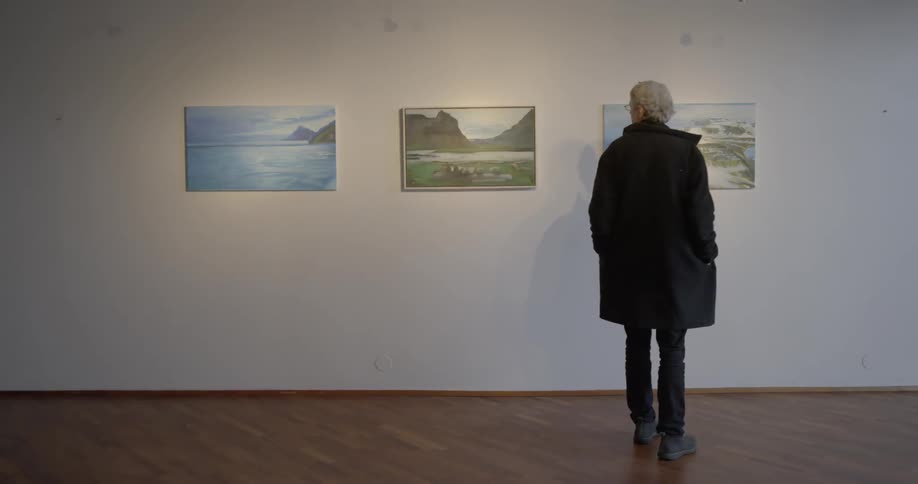 Man looks at paintings hanging in a gallery