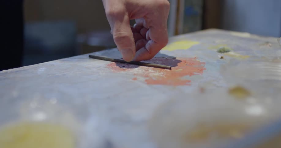 A man picks up a charcoal stick from a table
