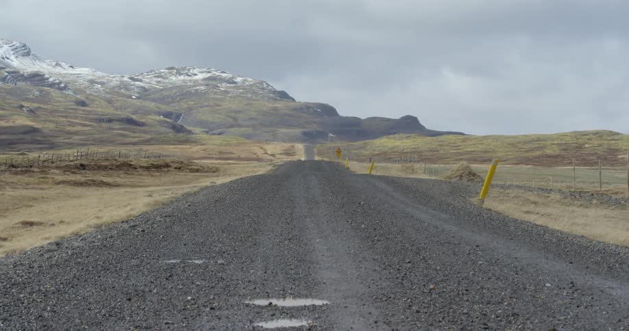 A black gravel road stretches across the remote landscape