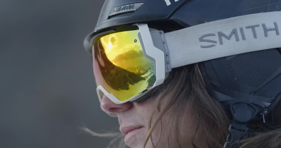 A man's ski goggles are reflecting his setting as he stands outside during the day