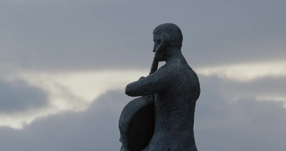 A stone statue of a man playing the cello