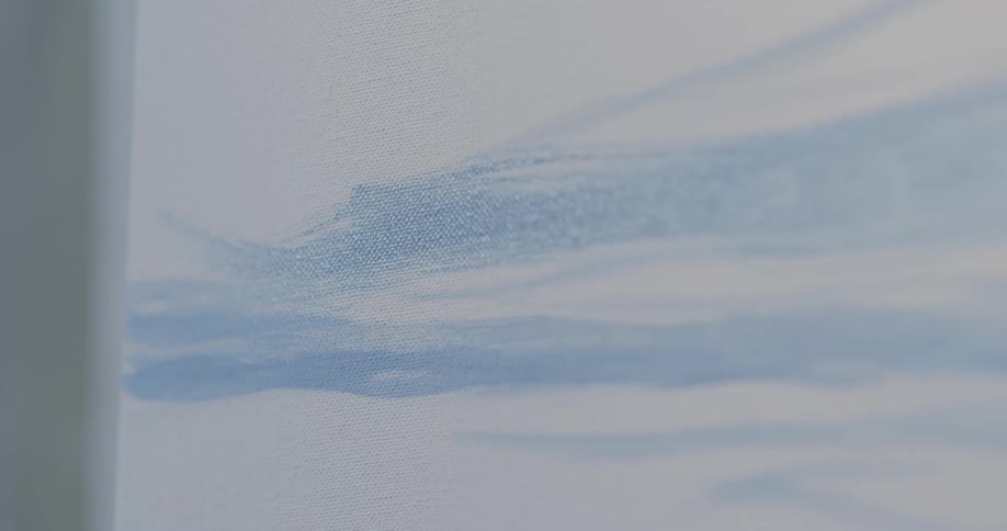An artist is using a brush to apply paint to a canvas