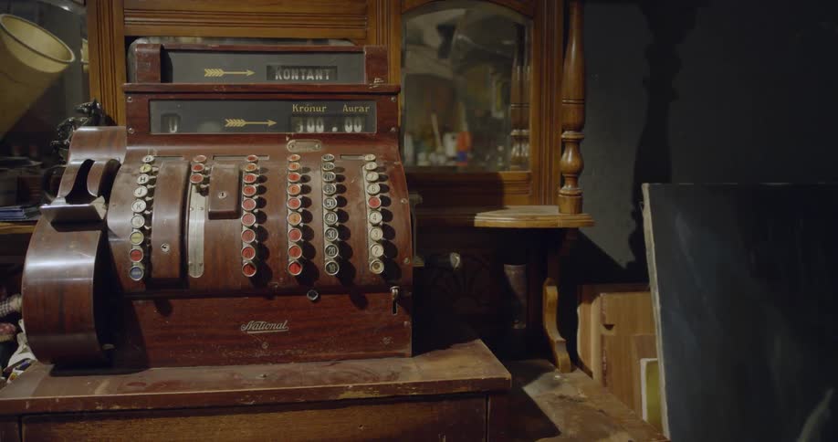 A man walks by an antique cash register in reflection of mirror