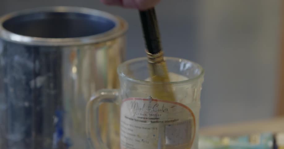 An artist dips their brush in water