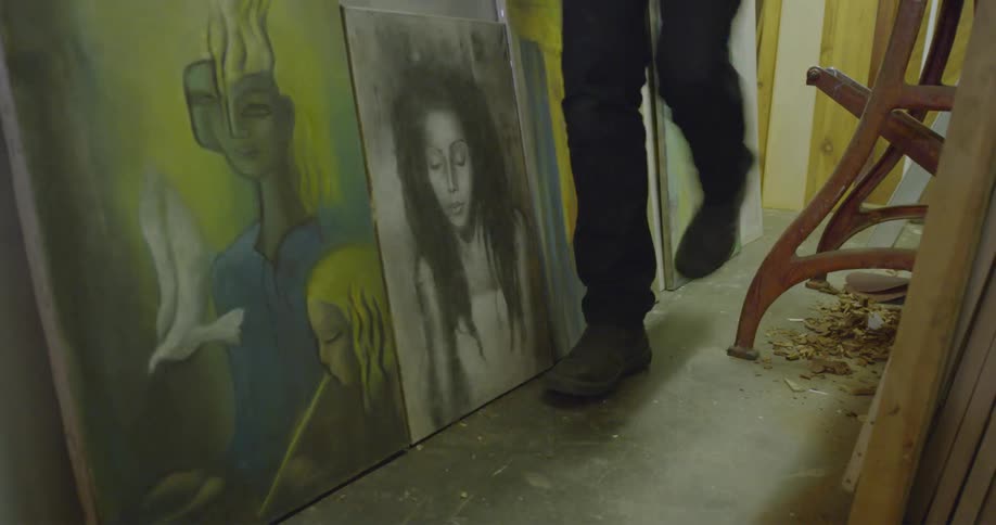 A person walks past some paintings in an art studio