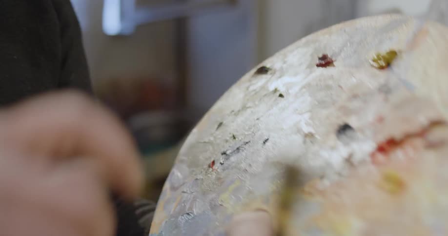 An artist mixes paint on a palette