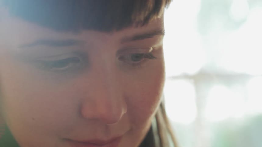 A woman smiles as she looks down at something