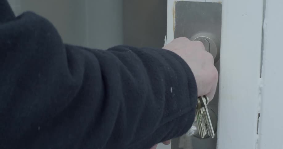 A person unlocks a door with large bundle of keys and walks inside