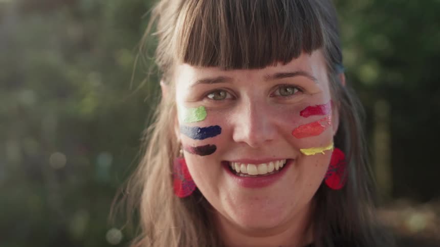 A woman with paint on her face smiles