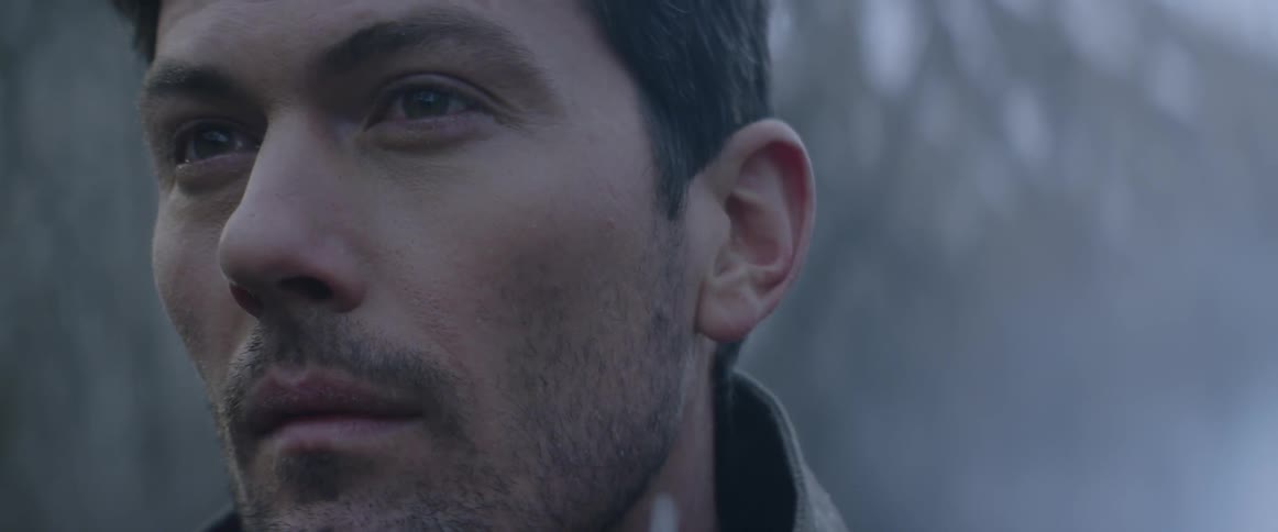 Man looking around outdoors as it slowly snows around him
