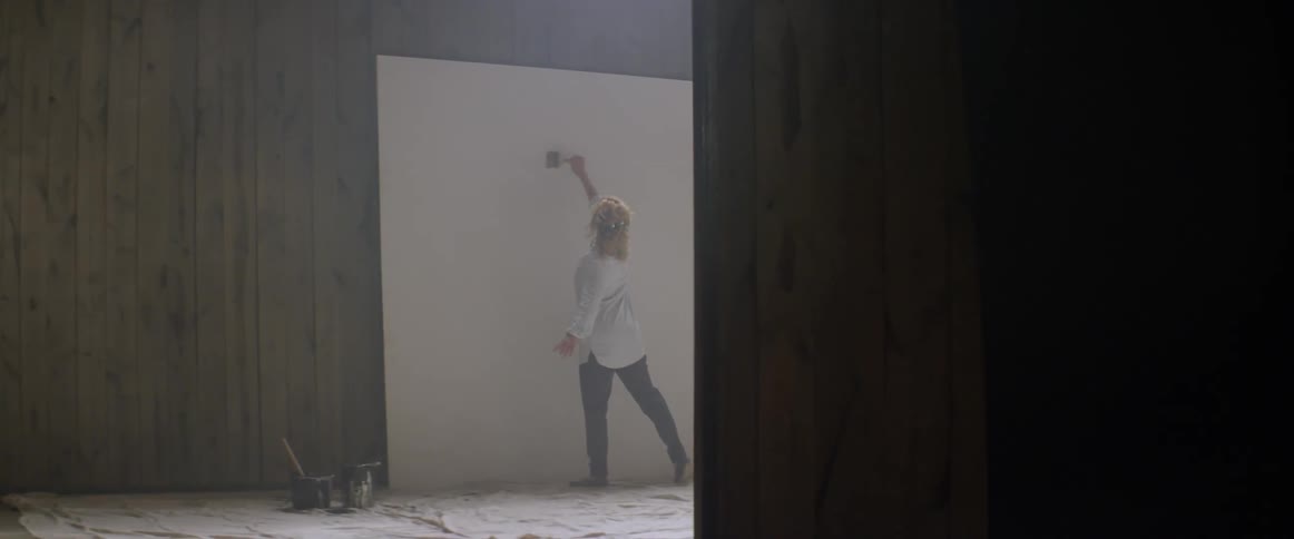 A woman prepares to paint on a large canvas
