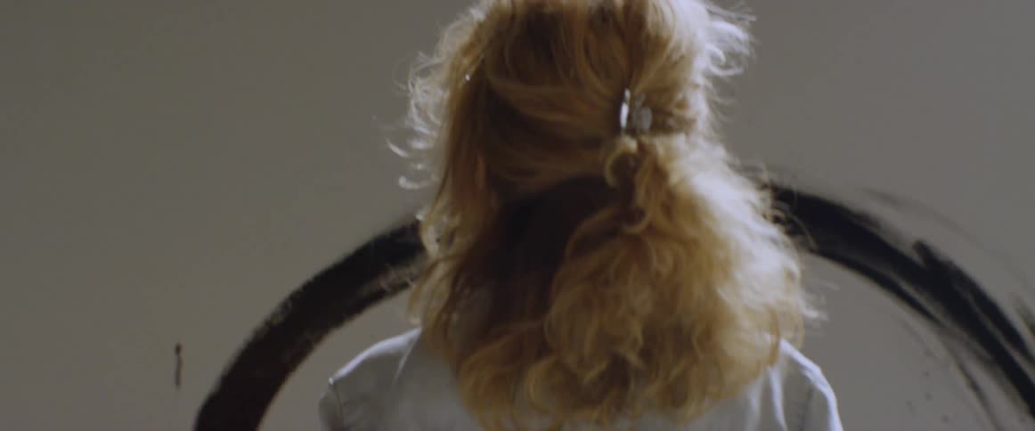 A female artist is staring at a canvas inside during the day