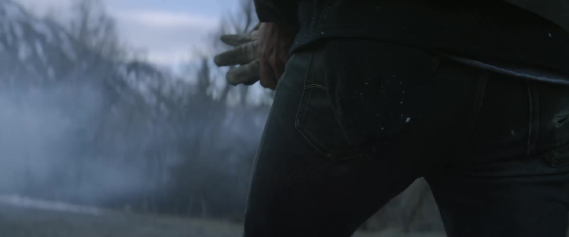 Person wiping their gloves on a coat sleeve as they remove them on a snowy and cloudy day