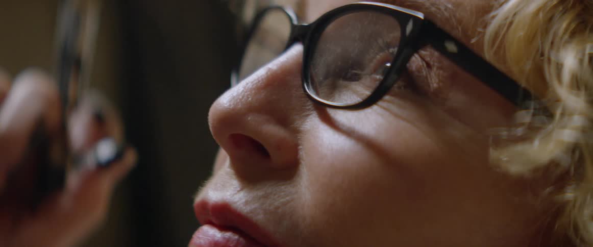 A woman wearing glasses is painting