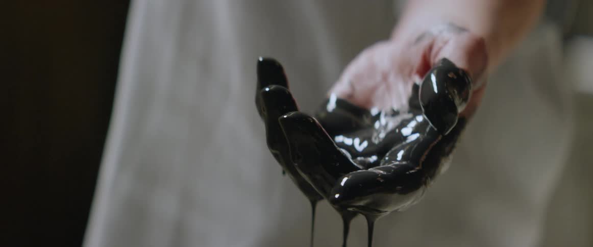 A woman dips her hand in black paint