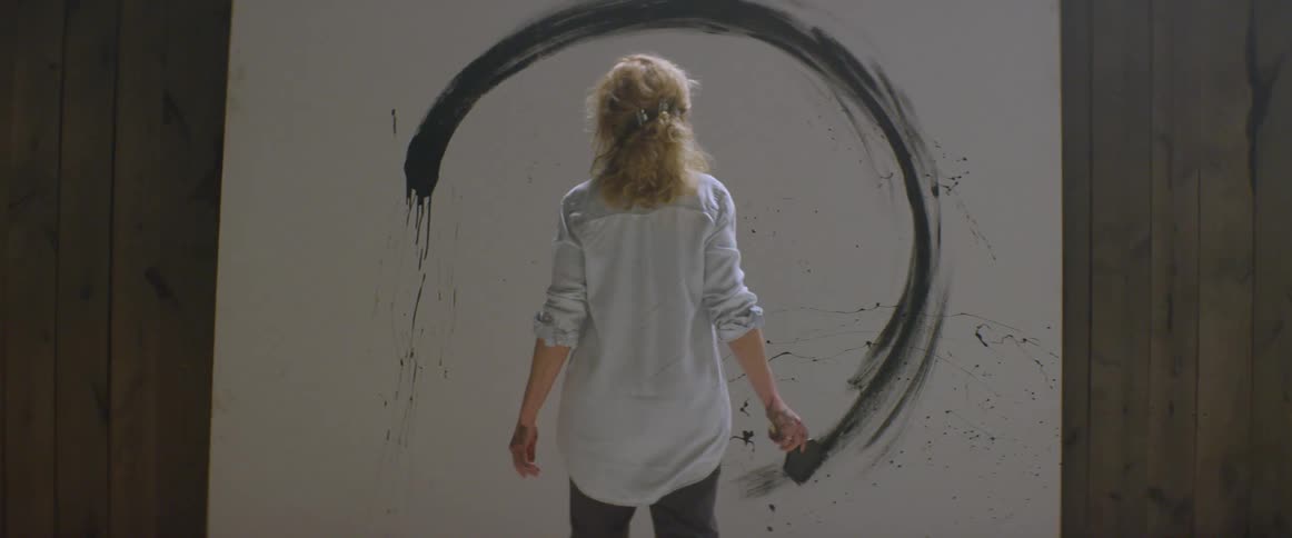 A woman paints on a large canvas
