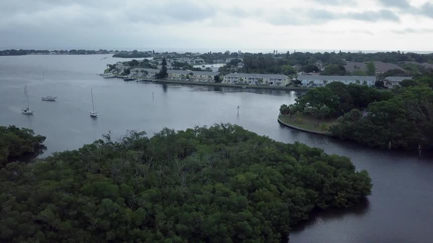 The boats are docked by the coast town with their sails down