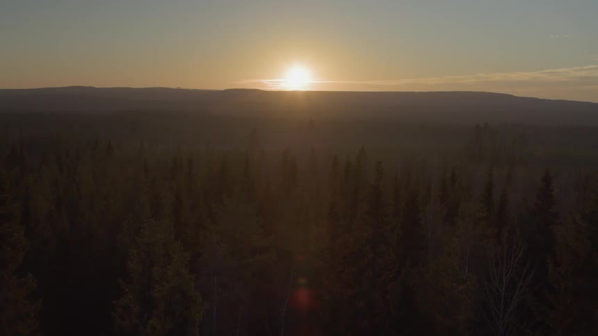 The sun is setting beyond hills in a natural setting
