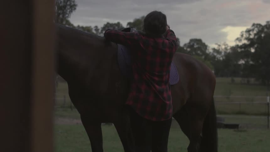 A person saddling up a horse