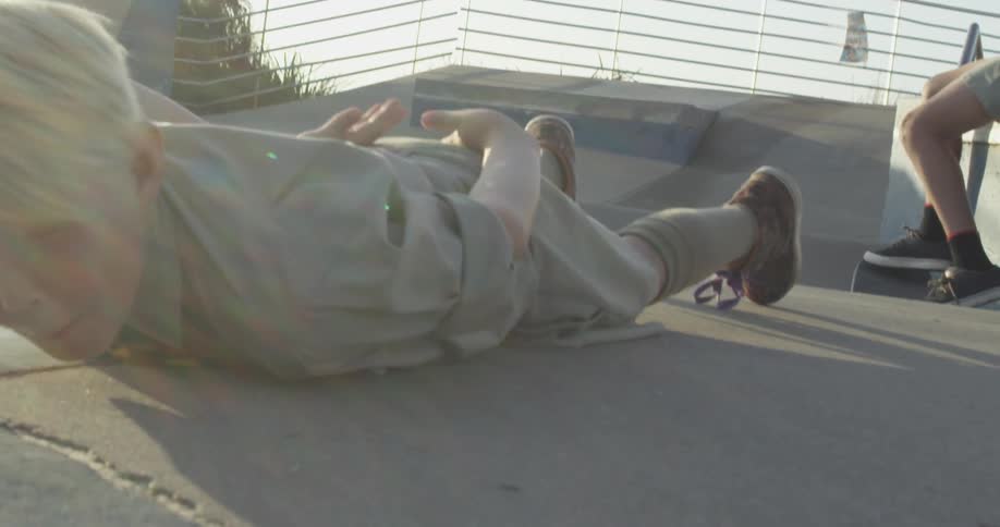 A white kid jumps over another white kid on a skateboard