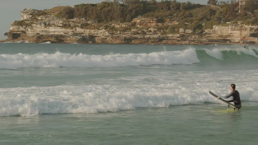 Man jumps onto a surfboard in an ocean