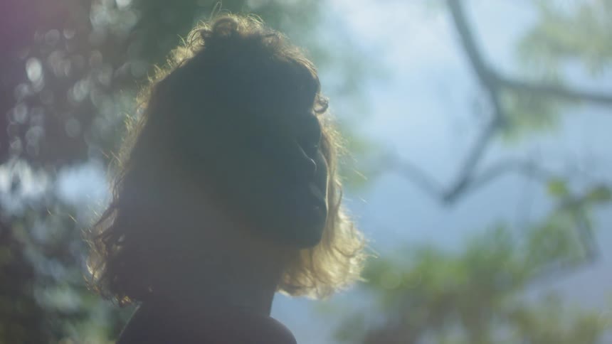 A woman stands out under a tree as the sun shines