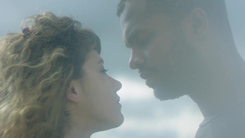 A man and woman are leaning in for a kiss outside during the day