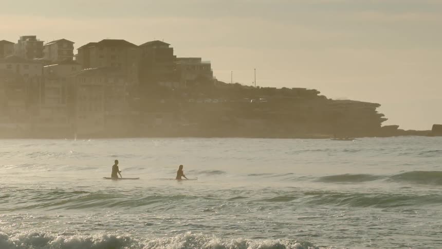 Surfers sitting on their boards in the water close to shore
