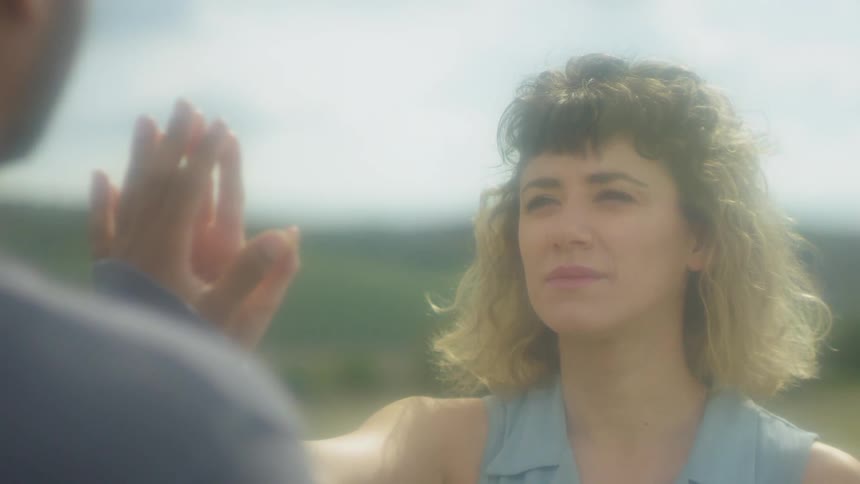 A man and woman touch hands outside