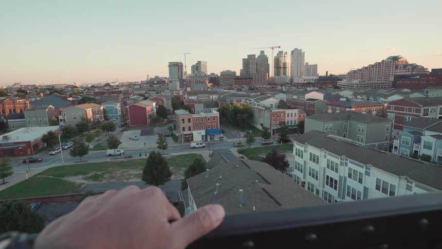 A person is leaning on the railing looking over a town