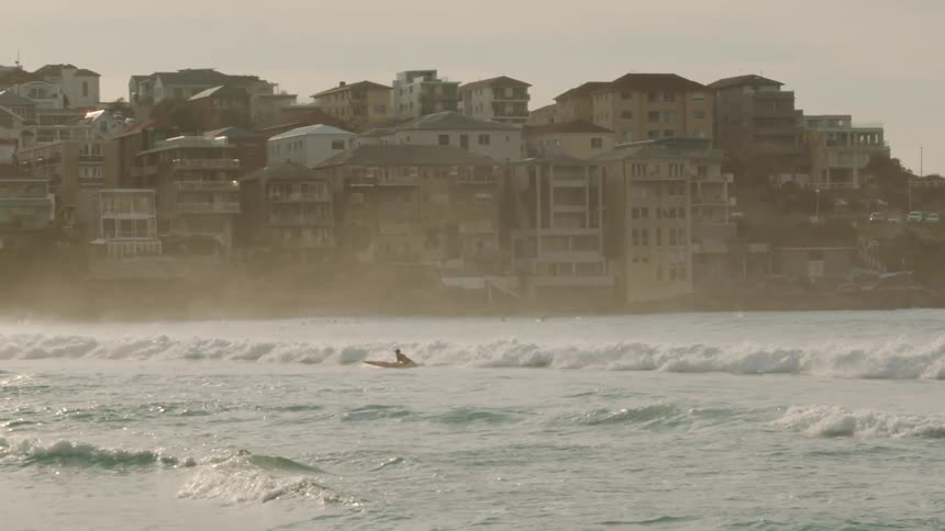 Person rides surfboard on the ocean waves