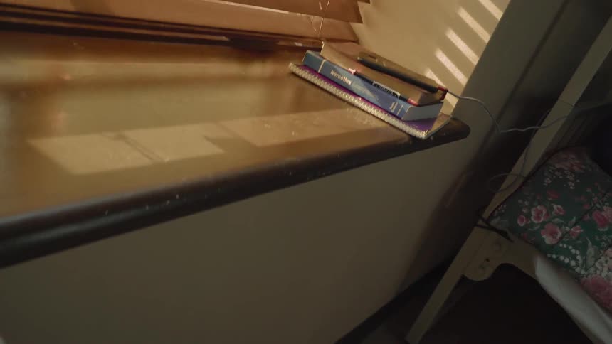 A person sleeps in a bed next to a window with books on the sill