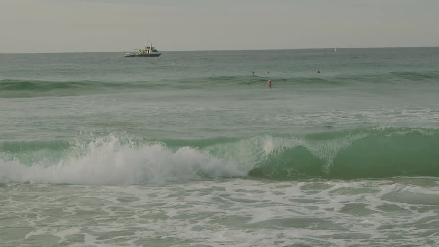 A man in a speedo dives into the ocean water