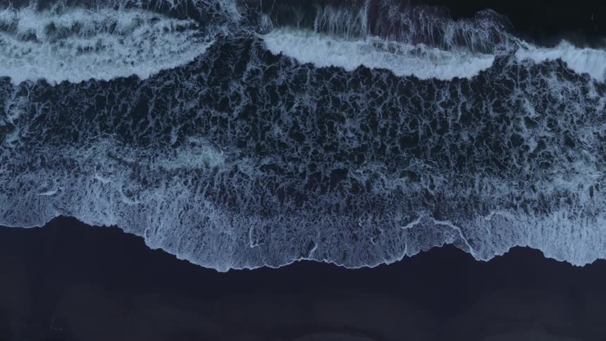 Waves are lapping the sand on a beach at dusk