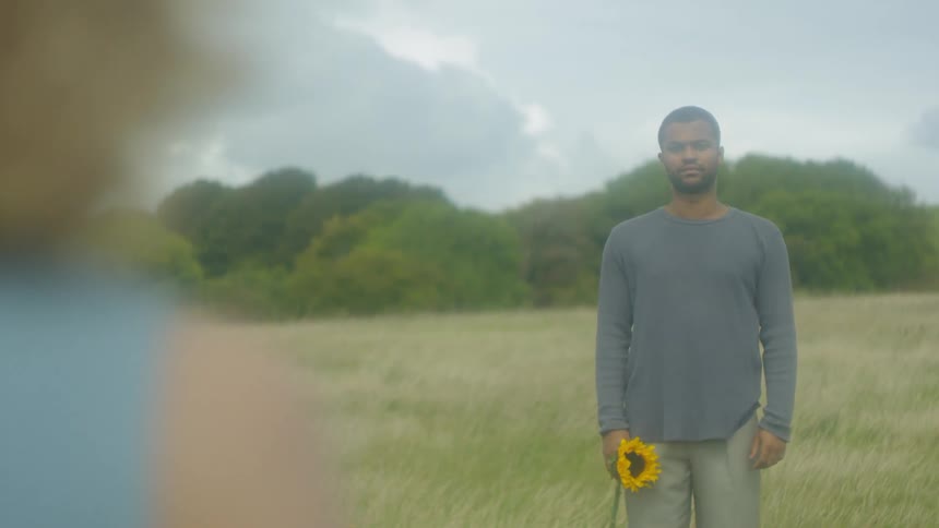 A man holds a sunflower in a field