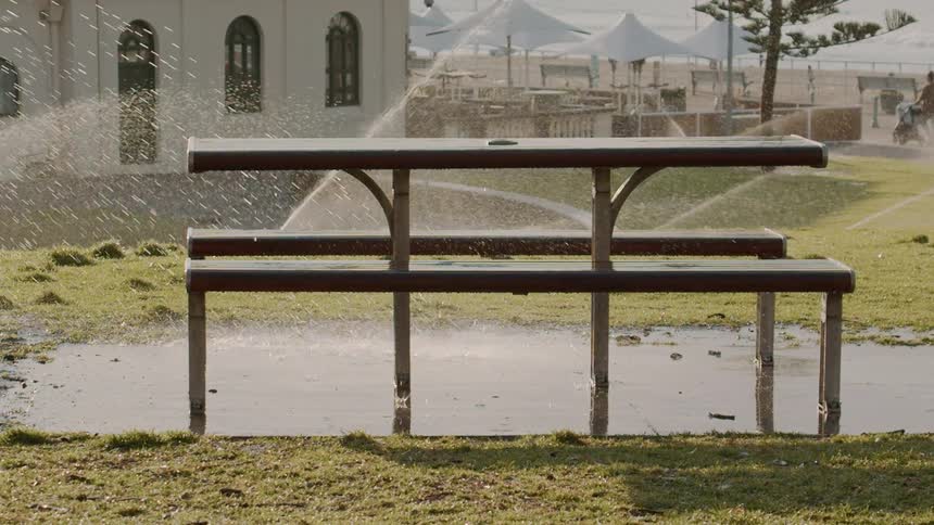 Sprinklers water grass around a picnic table