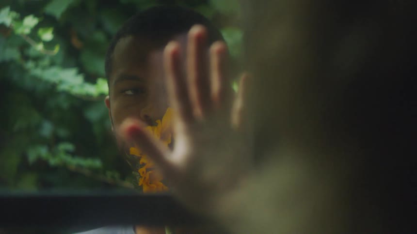 Woman puts her hand on a window while looking at a man outside