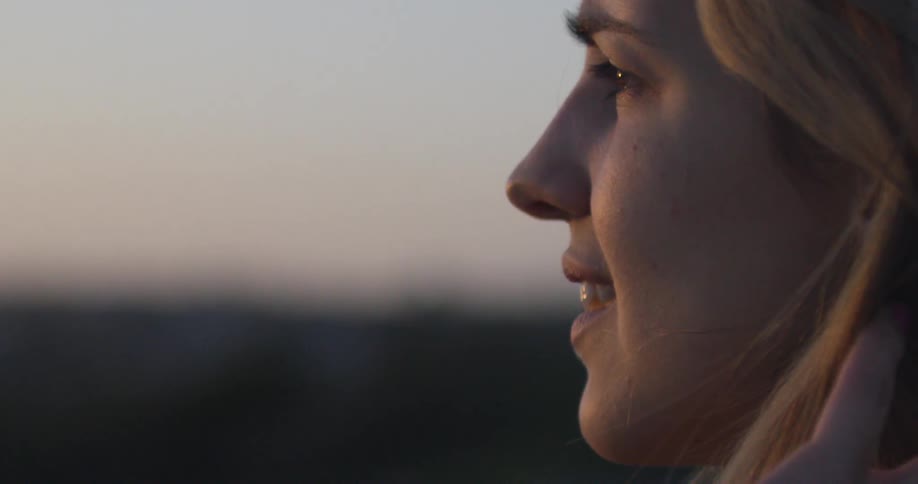 A woman looks out into the horizon at sunset