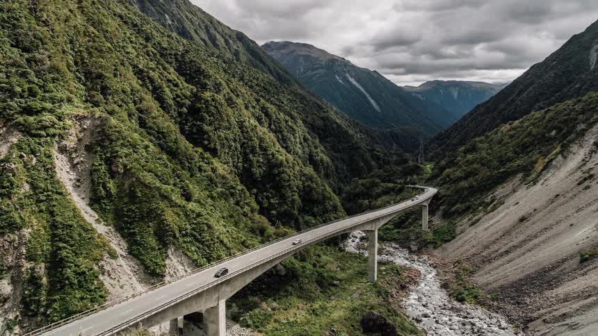 Vehicles pass along a bridge in the mountains