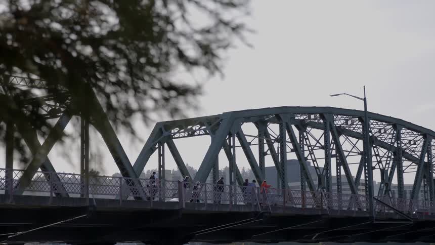 People travel over the bridge by foot and vehicle
