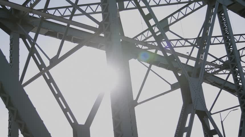 The sun shines through bridge beams