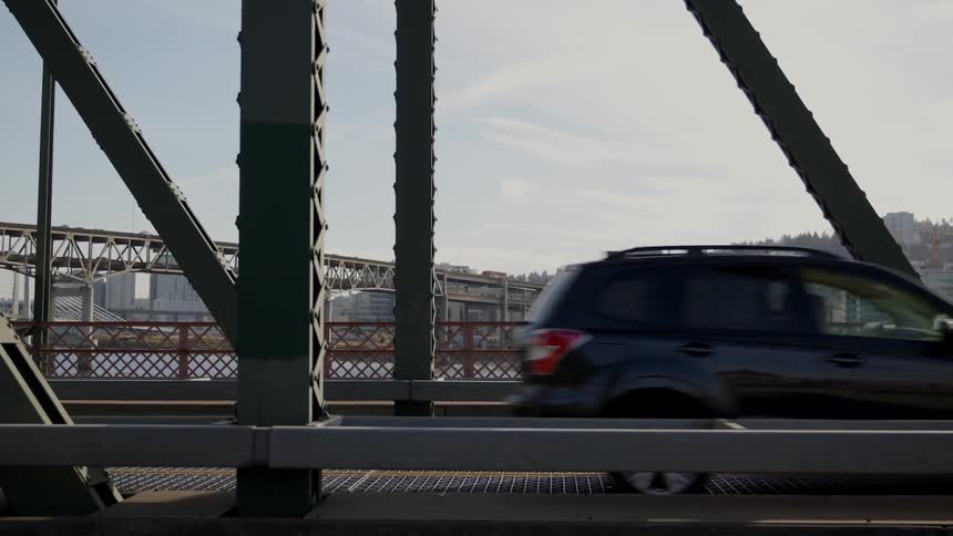 Vehicles and bicyclists are driving on a bridge during the day