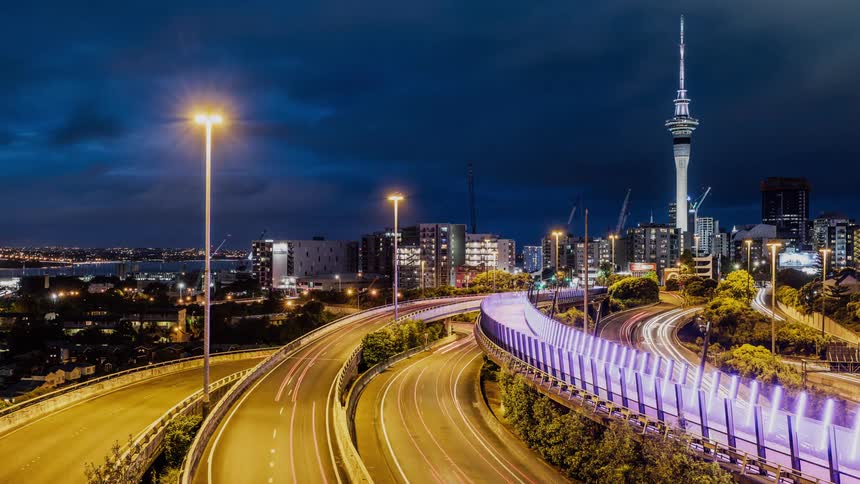 Clouds roll over a busy highway next to a city at night