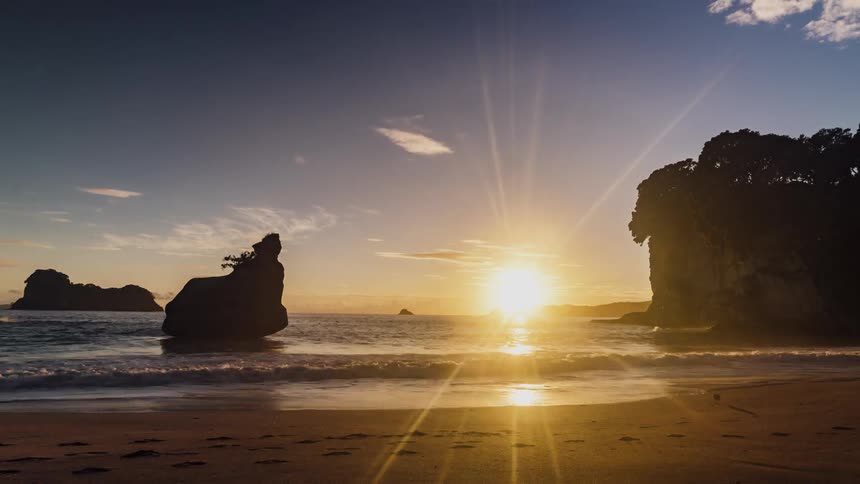 People are walking on a beach as the sun rises