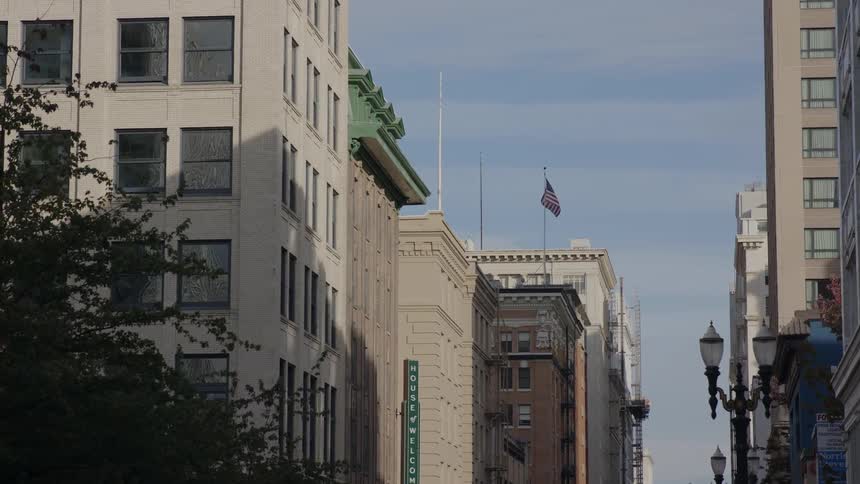 An american flag billows on top of a city building